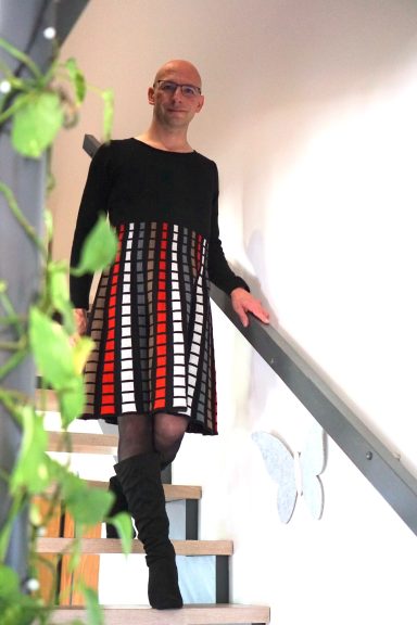 Person in einem gestreiften Kleid steht auf einer Treppe, umgeben von Pflanzen.