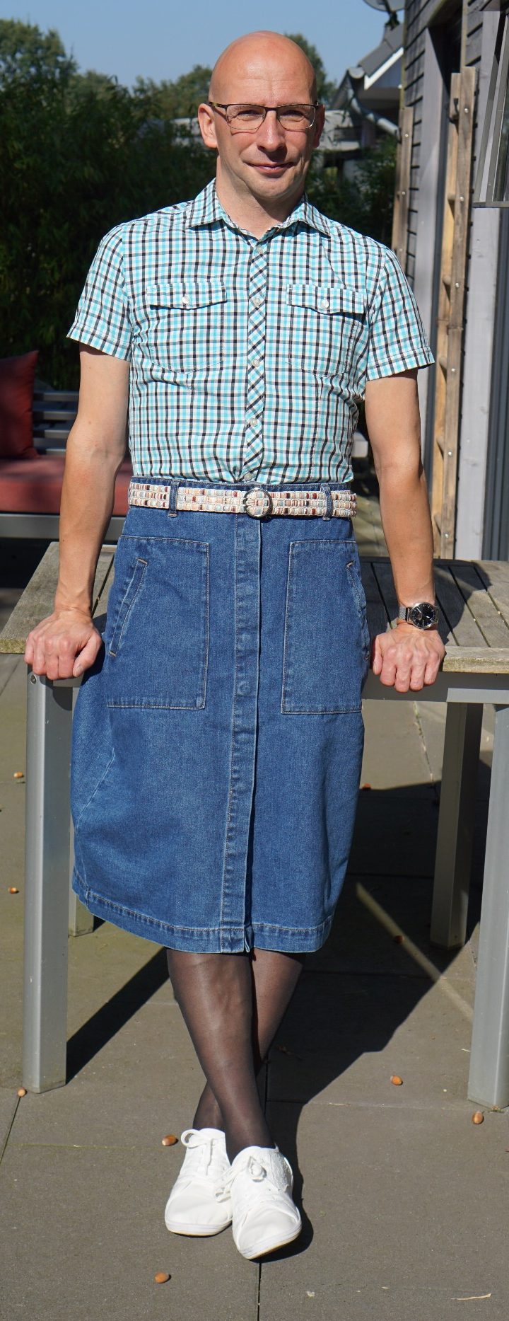 Mann in einem blauen Rock und Hemd, steht lächelnd im Freien.